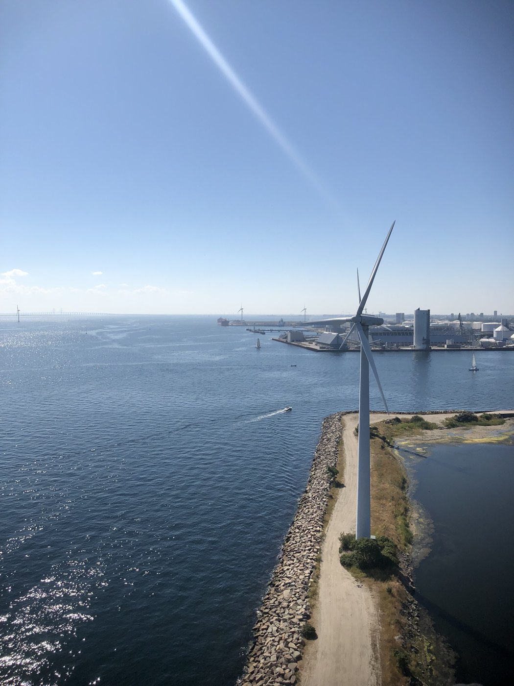 A wind turbine on a breakwater in Copenhagen harbour, seen from the top of another turbine