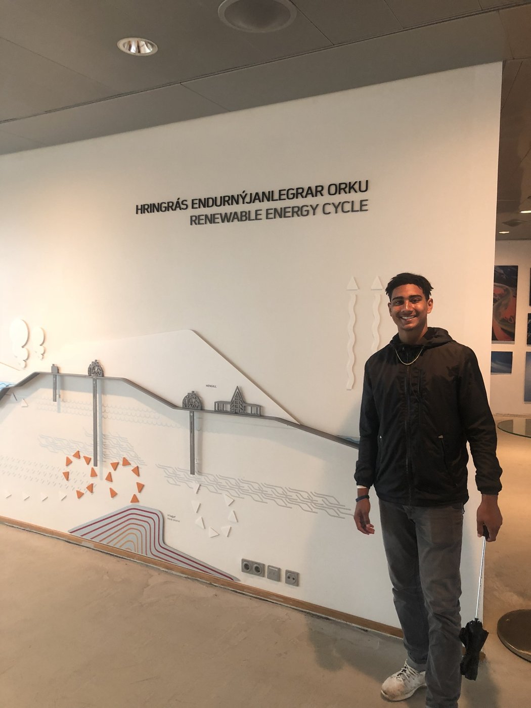 Jakobi beside a Renewable Energy Cycle wall diagram at a geothermal plant in Iceland